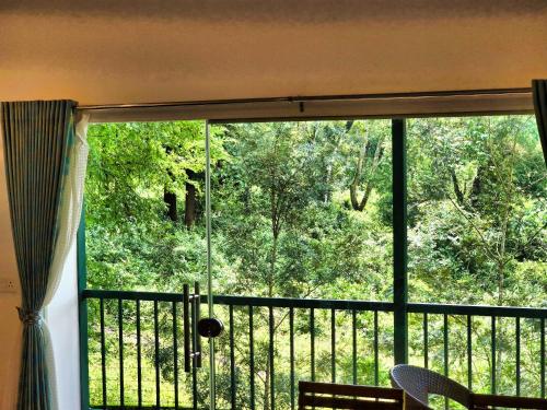 a window with a view of the woods from a balcony at Green BOB Villa in Sultan Bathery