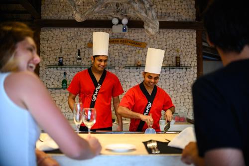 two chefs standing in a kitchen preparing food at Diamonds Thudufushi Maldives Resort & Spa in Thundufushi