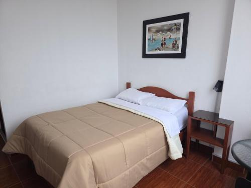 Un dormitorio con una cama y un cuadro en la pared. en Hospedaje Grau, en Puerto Chicama