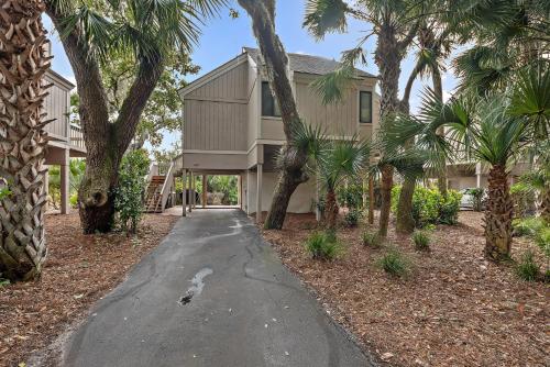 a house with palm trees in front of a driveway at 818 Treeloft Cottage in Seabrook Island