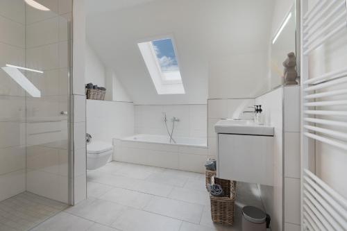 a white bathroom with a sink and a bath tub at Meerperle - Sauna und überdachte Terrasse, Hunde willkommen! in Fedderwardersiel