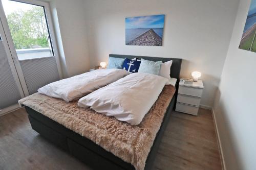 a bedroom with a large bed with white and blue pillows at KÜSTE33/48 – Penthousewohnung mit Dachterrasse, Sauna - strandnah! in Butjadingen OT Tossens