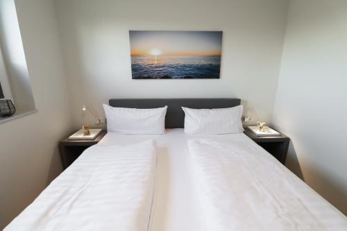 a bedroom with a large bed with two night stands at KÜSTE33/20 – Exklusive Ferienwohnung mit Sauna & nah am Strand! in Butjadingen OT Tossens