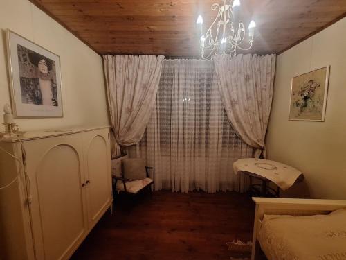 a bedroom with a window with curtains and a chandelier at Rent in summer in Ragaciems