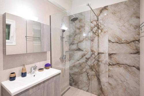 ein Badezimmer mit Dusche, Waschbecken und Spiegel in der Unterkunft Villa Olga Corfu by Villa Plus in Kontokali