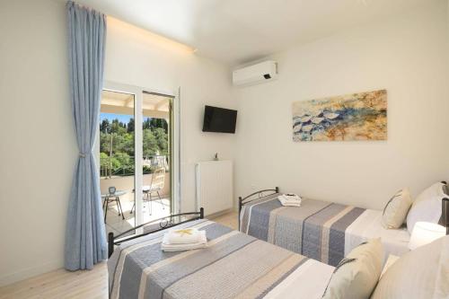 ein Hotelzimmer mit zwei Betten und Balkon in der Unterkunft Villa Olga Corfu by Villa Plus in Kontokali