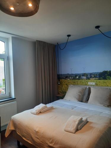 a bedroom with a large bed with two towels on it at LÖSS Wijnhotel en Smaaklokaal in Vijlen