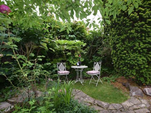 two chairs and a table in a garden at 5 Bed in Dunster 63301 in Dunster