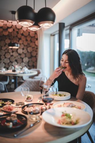 a woman sitting at a table eating food at Hotel Montis - Schönblick in Brunico