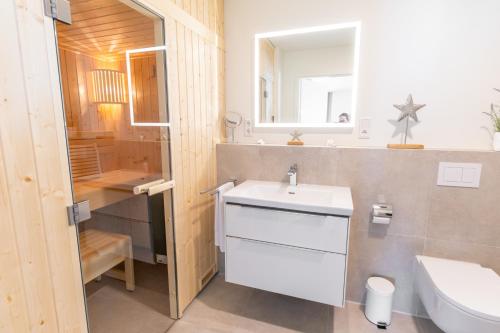 a bathroom with a white sink and a toilet at KüstenPerle - Penthousewohnung mit 2 Schlafzimmern und Sauna in Butjadingen OT Tossens