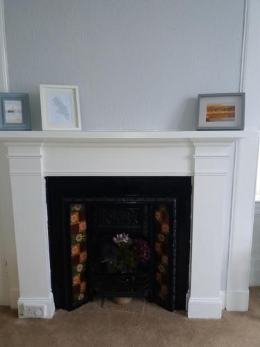 a fireplace with two pictures on top of it at The Port in Port Bannatyne