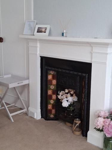 a fireplace with a white mantle with flowers on it at The Port in Port Bannatyne