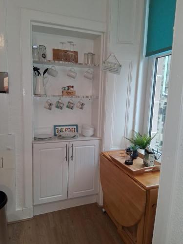 a kitchen with a white cabinet and a window at The Port in Port Bannatyne