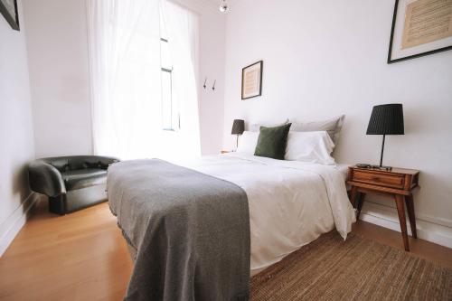 a white bedroom with a bed and a chair at House Sao Bento in Lisbon
