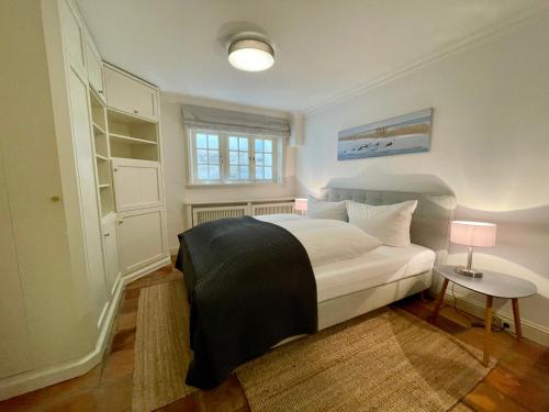 a bedroom with a large white bed and a window at Sylt Glück in Morsum