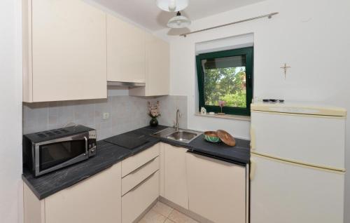 a white kitchen with a microwave and a sink at Eight-Bedroom Holiday Home In Pasman in Pašman