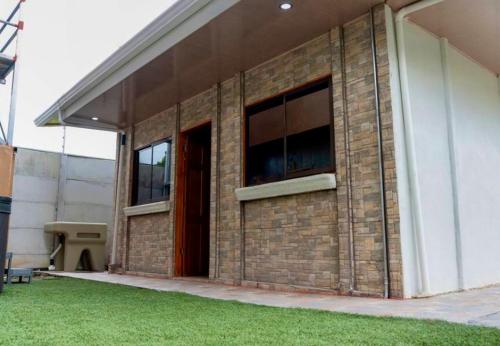 a brick building with two windows and a red door at Good Vibes Apartments in Talamanca