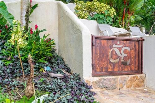 a wooden gate in a garden with white chairs at Privacy-waterfall-pool-sleeps 8-near Beach in Matapalo