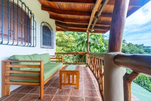 a porch with a green couch and a table at Privacy-waterfall-pool-sleeps 8-near Beach in Matapalo