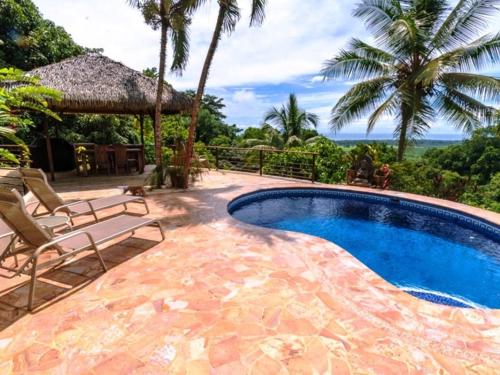 a swimming pool with two chairs and a umbrella at Privacy-waterfall-pool-sleeps 8-near Beach in Matapalo