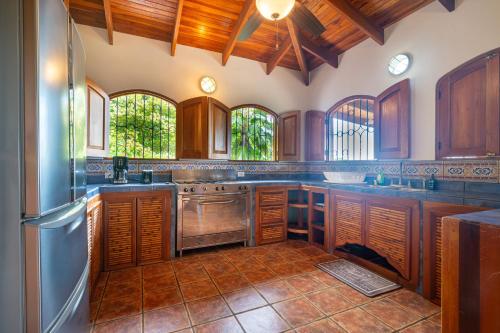 a large kitchen with wooden cabinets and stainless steel appliances at Privacy-waterfall-pool-sleeps 8-near Beach in Matapalo