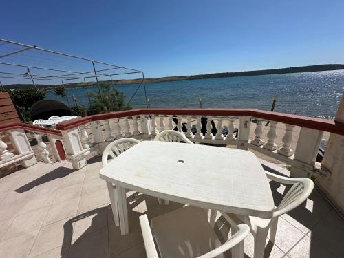 a white table and chairs on a balcony overlooking the water at Villa M ground floor Apartment for 4 persons in Ljubač