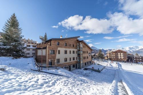 a building in the snow with mountains in the background at Hotiday Sauze Centro in Sauze d'Oulx