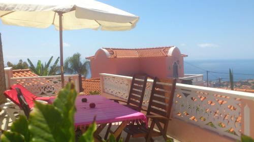 a table and chairs on a balcony with an umbrella at Casa do Poço Funchal in Funchal