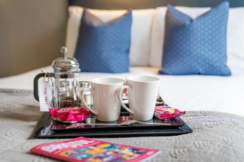 a tray with two coffee mugs and a tea set on a bed at The Washington in Bristol