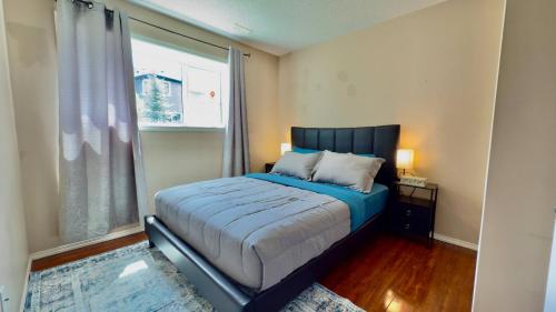 a bedroom with a bed with a blue comforter and a window at The Panatella Pad /Guest’s Private Suite in Calgary