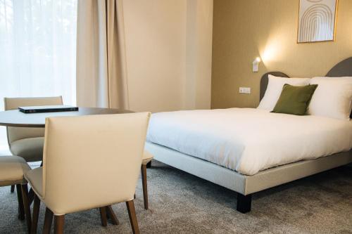 a hotel room with a bed and a table at Résidence Bordeaux Sud Pessac in Pessac