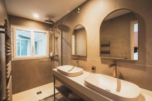 two sinks in a bathroom with two mirrors at Parc Victoria Appartements in Saint-Jean-de-Luz