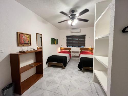 a bedroom with two beds and a ceiling fan at Casa Puerto Morelos in Puerto Morelos