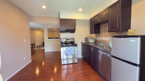 a kitchen with stainless steel appliances and wooden floors at The Panatella Pad /Guest’s Private Suite in Calgary