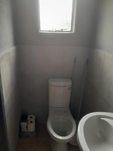 a bathroom with a toilet and a sink and a window at Twala trails lodge in Midrand