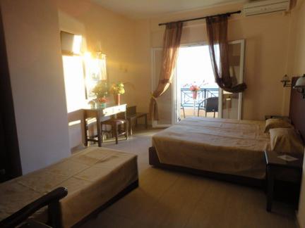 a hotel room with two beds and a window at Galini Sea Apartments in Benitses