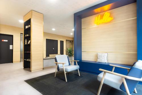 un hall avec deux chaises et un mur avec un panneau Nissan dans l'établissement City Résidence Paris Saint-Maurice, à Saint-Maurice
