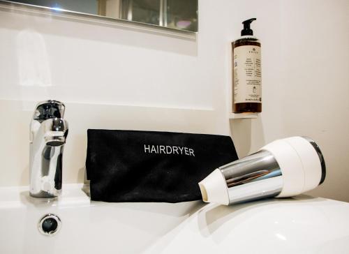 a blow dryer and a bottle of wine on a sink at Résidence Bordeaux Sud Pessac in Pessac
