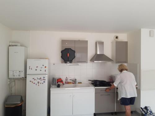 une femme debout dans une cuisine avec un évier dans l'établissement Les vergers, à Fouras
