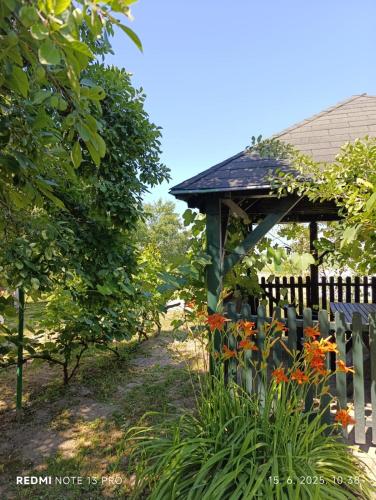 a wooden gazebo in a garden next to a fence at Ruralna kuća za odmor Bor Anya in Vardarac