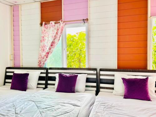 a bedroom with a bed with purple and white pillows at Pink house by Home one love in Phra Nakhon Si Ayutthaya