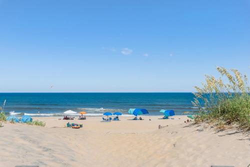 a group of people sitting on a beach with umbrellas at Quite Right in Nags Head