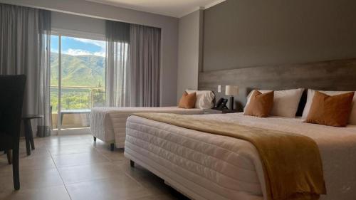 a hotel room with two beds and a large window at Gran Hotel Cosquin in Cosquín