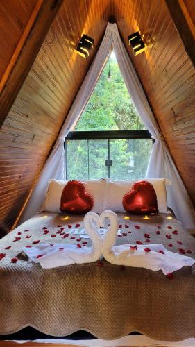 a bed with two swans made out of hearts at Chalé romântico São Bento do Sapucaí - Jacuzzi - Chalé Gênova in São Bento do Sapucaí
