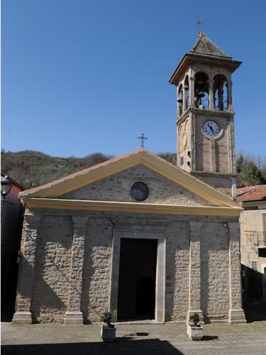 a stone church with a clock tower and a door at Il Piazzale B&B in Filiano