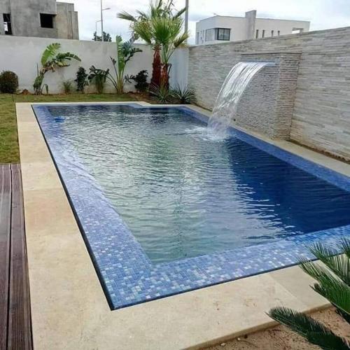 a swimming pool with a waterfall in a backyard at Puerto Azul in Mongón