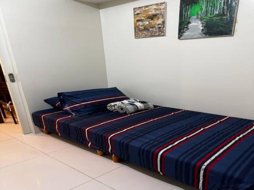 a bedroom with a bed with a striped blanket at Cozy Brenthill Condo in Baguio City - Entire House Rental in Baguio