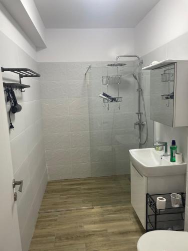 a white bathroom with a shower and a sink at Răsărit la epava in Costinesti