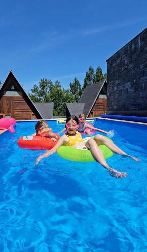 three children laying on rafts in a swimming pool at AKORD chata in Námestovo