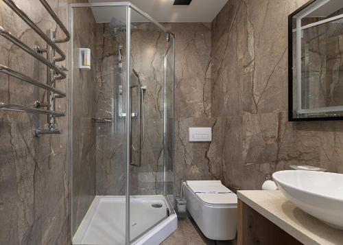 a bathroom with a shower and a toilet and a sink at Chalet Podgorie Spa&Resort in Bukovel